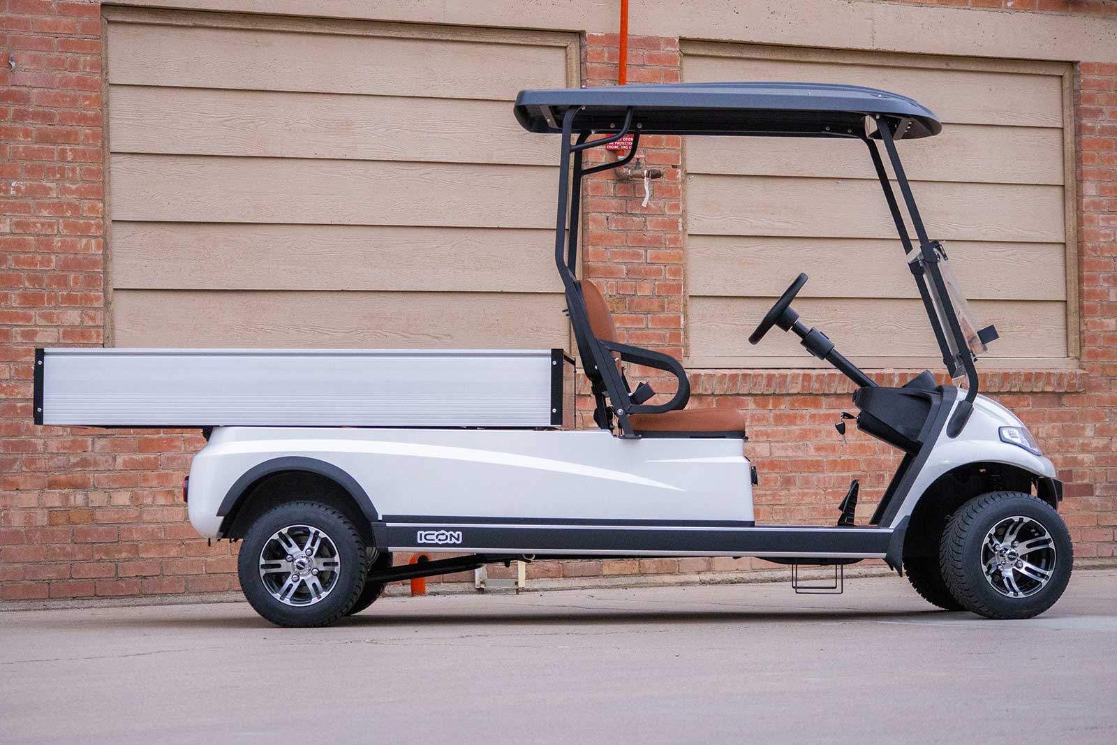 ICON C20U commercial utility golf cart with extended flat cargo bed parked at industrial building — commercial campus and warehouse logistics configuration